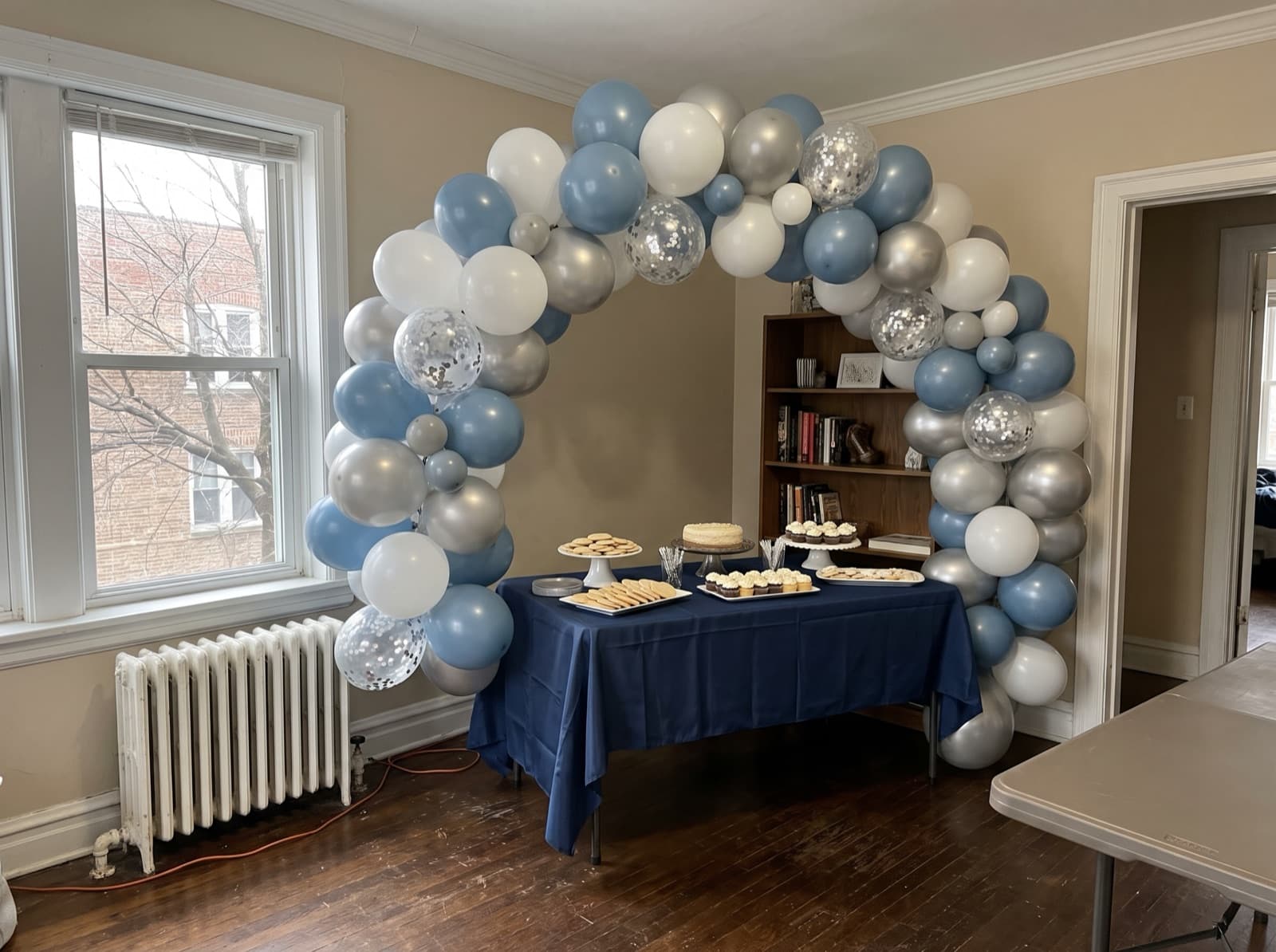 Organic balloon arch in dusty blue, white and silver over a dessert table at a Chicago birthday party
