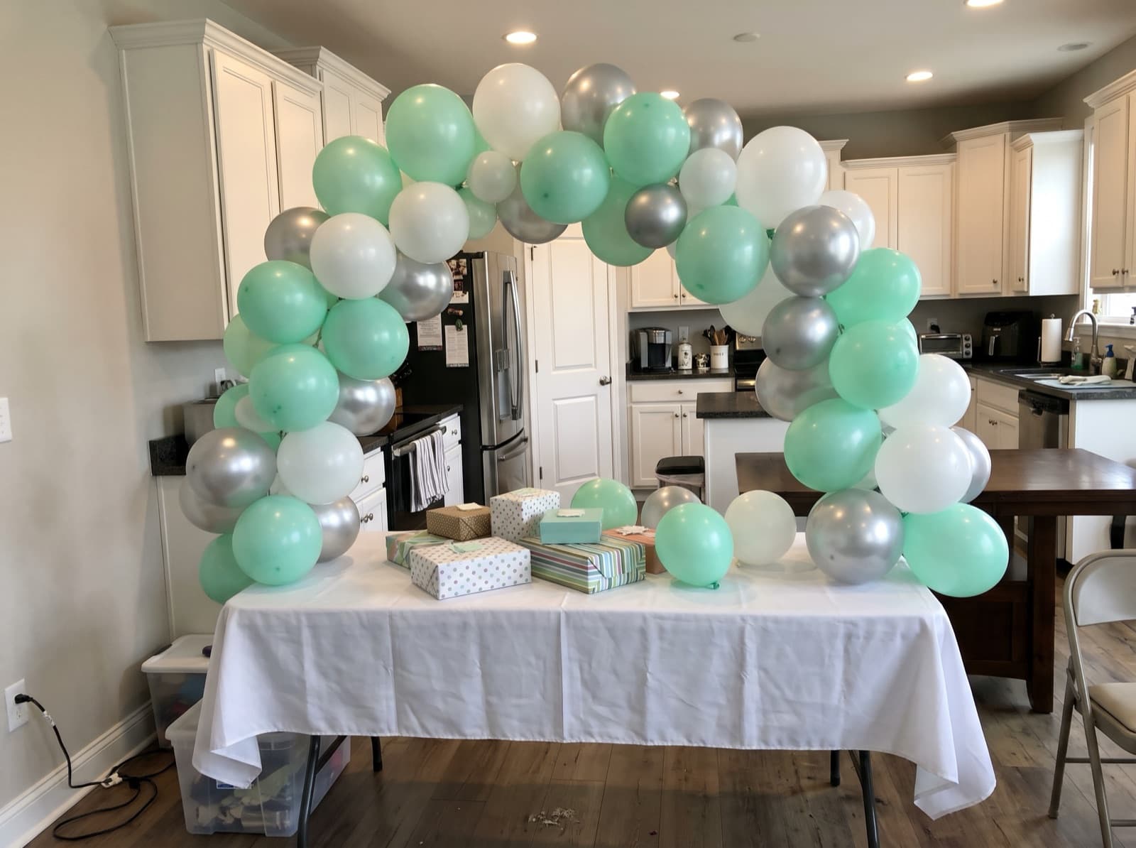 Mini tabletop balloon arch in mint, white and silver over a gift table